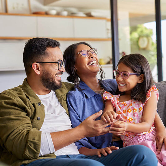 Parents modeling healthy relationships by smiling and connecting lovingly with their daughter at home