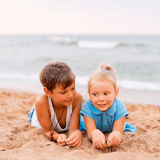 Two young siblings playing calmly together on a beach, symbolizing peaceful connection and positive sibling relationships through loving limits.